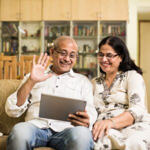 indian-asian-senior-couple-video-chatting-tablet-computer-while-sitting-couch-garden-home-selective-focus (1)